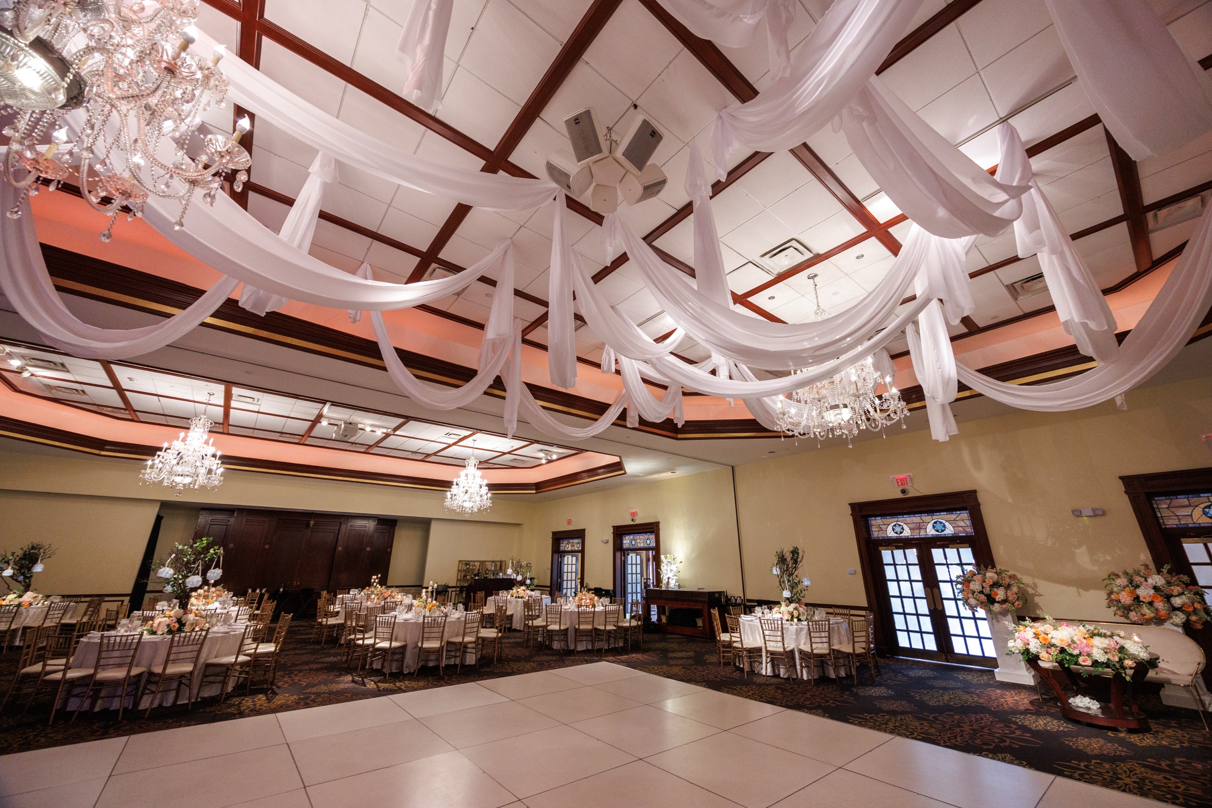 Grand Ballroom prepared for a reception beneath chandeliers and flowing white ceiling drapery
