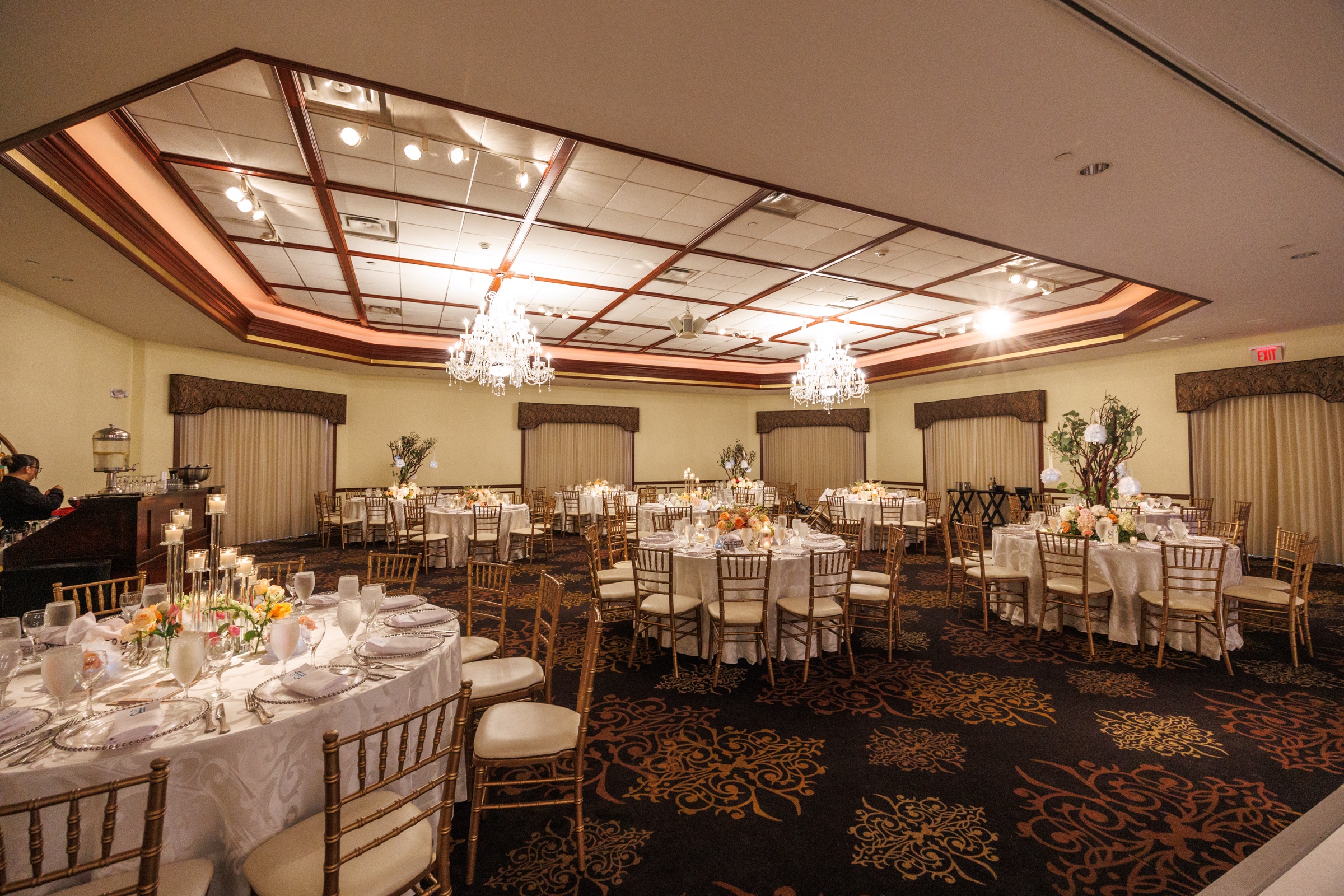 Wide view of the Grand Ballroom set with round tables, warm lighting, and floral centerpieces