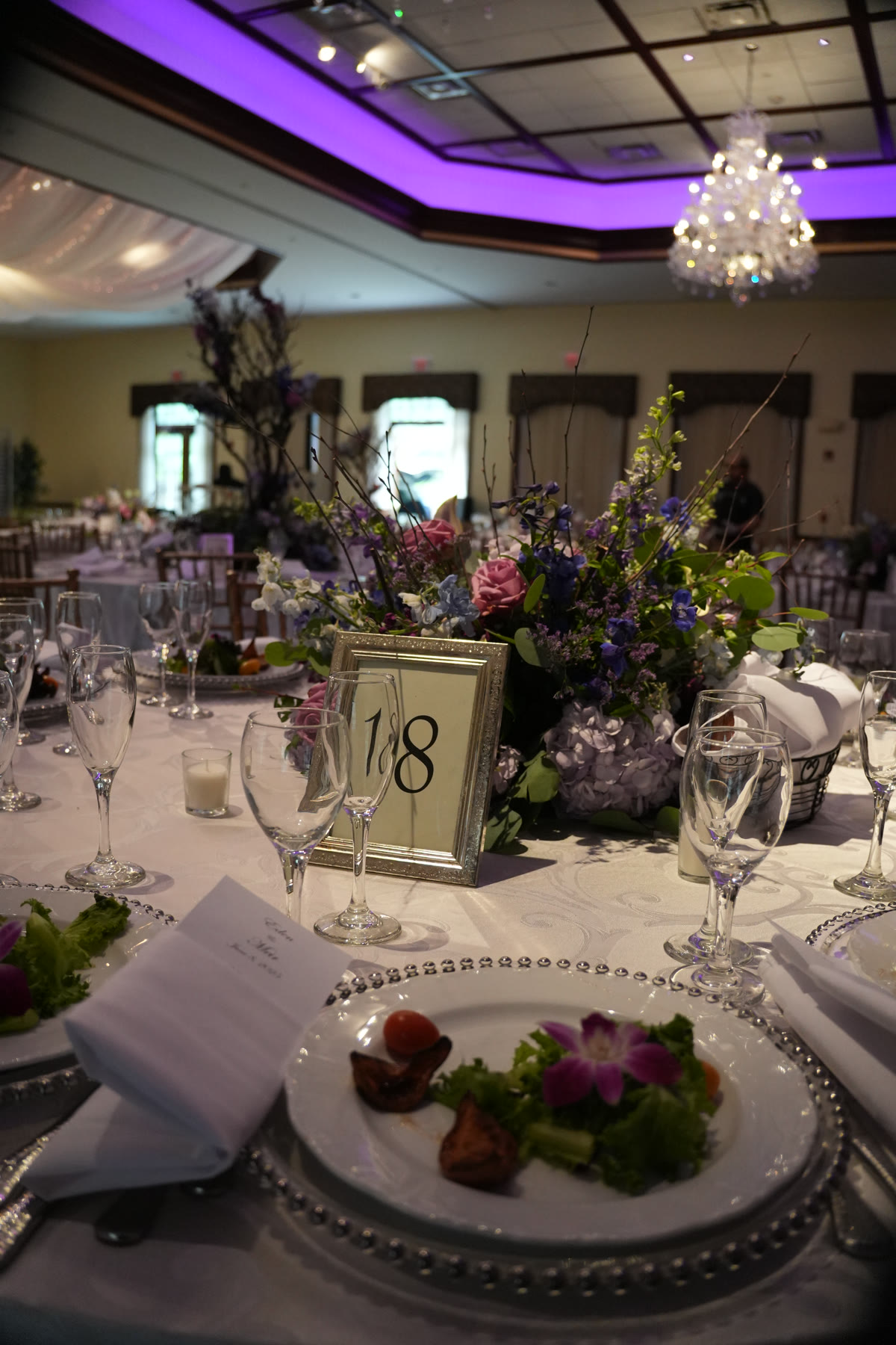 Grand Ballroom table setting with glassware, plated salad, and floral centerpiece