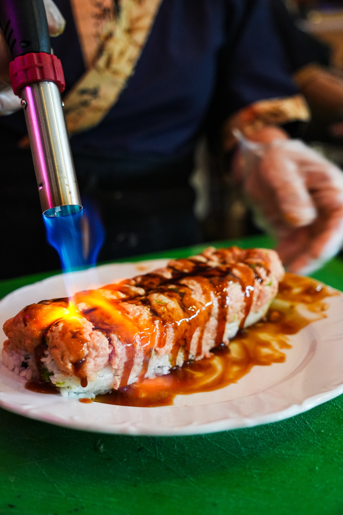 Chef torching a sushi station item