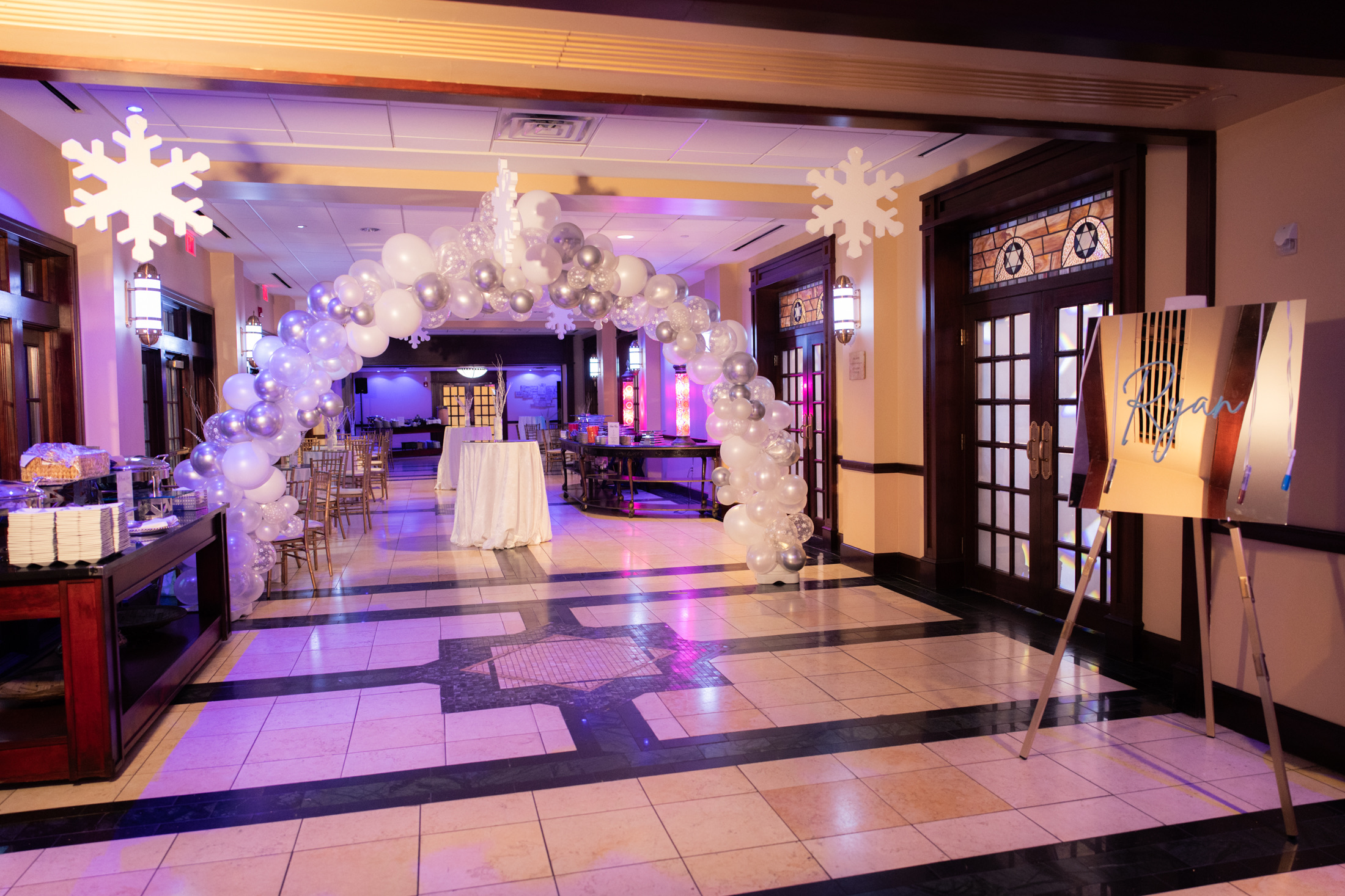 Silver and white balloon arch welcoming guests to a mitzvah celebration