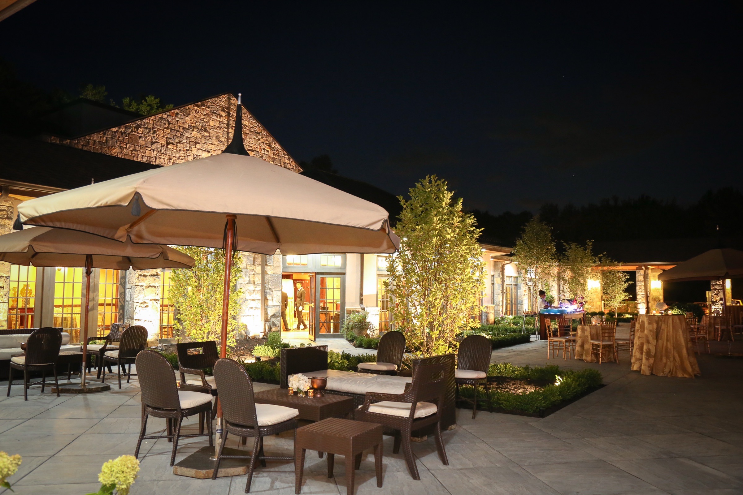 Outdoor courtyard lounge seating beneath umbrellas at night