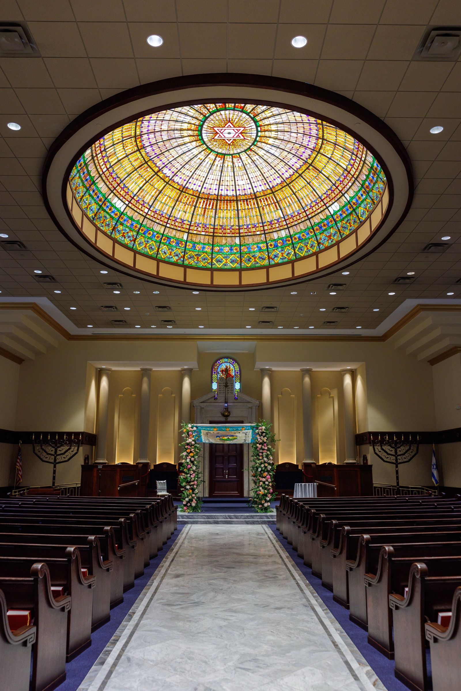 Sanctuary aisle and floral chuppah beneath the stained-glass dome