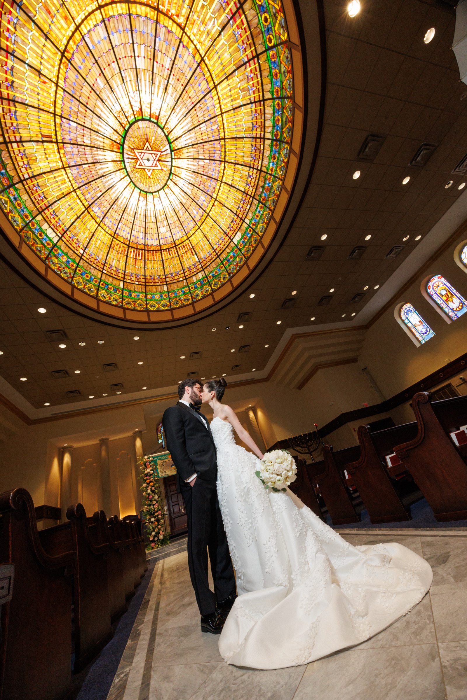 Newlyweds beneath the illuminated stained-glass dome in the sanctuary